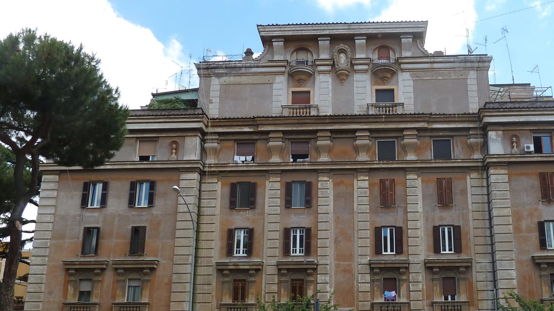 Facciata di un palazzo su via Appia Nuova: persiane spaiate, panni stesi, antenne