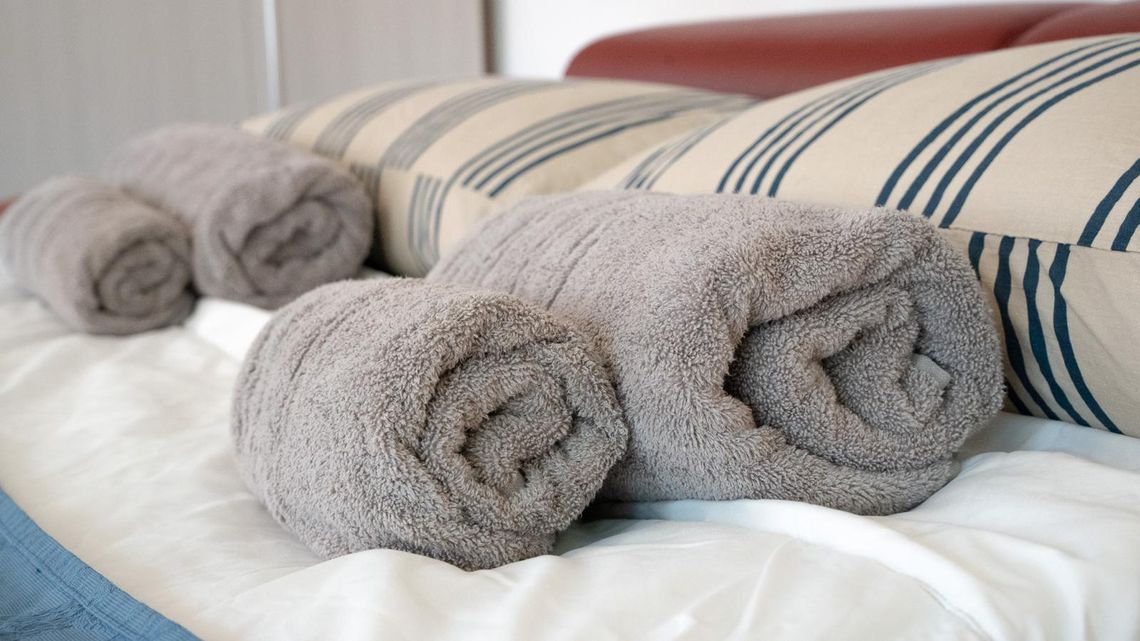 Asciugamani arrotolati sul letto, accanto ai cuscini a righe